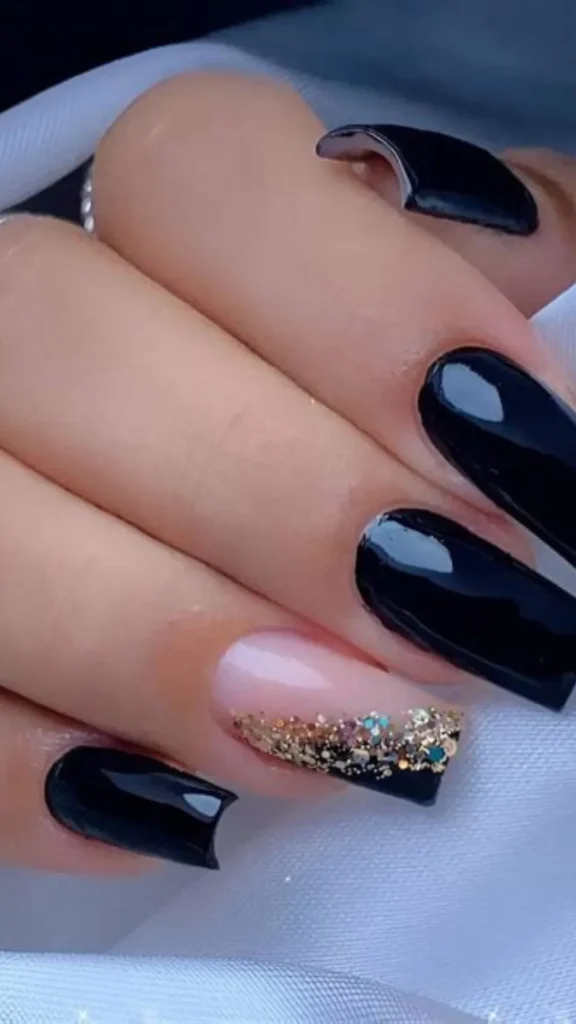 An edgy and modern wedding manicure featuring long, square-shaped nails painted in a high-gloss, solid black polish. The ring finger serves as an accent nail with a sheer nude base and a sweeping gradient of chunky gold glitter flakes near the tip.