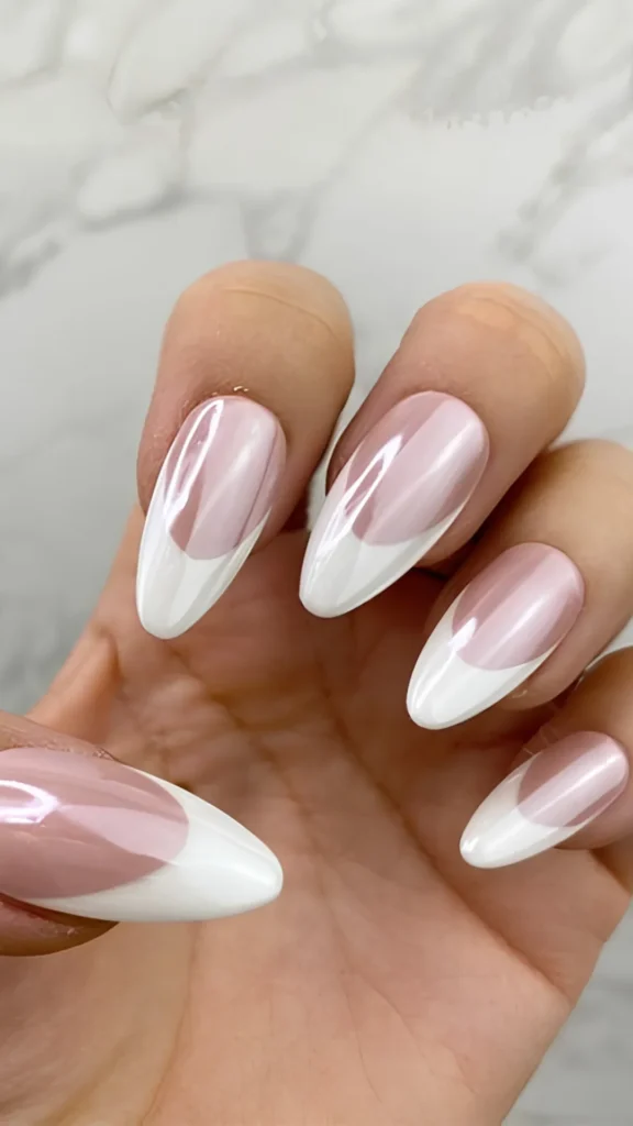 An almond-shaped manicure showcasing a creative twist on the classic French style, featuring smooth, natural nude bases tipped with stark, crisp white smiles, all finished with a glossy chrome glaze.