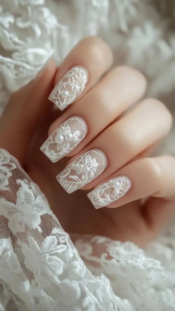 An intricate lace bridal nail art design on long, square-shaped nails, featuring ultra-detailed white floral lace patterns over a sheer nude base, embellished with tiny 3D white pearls.