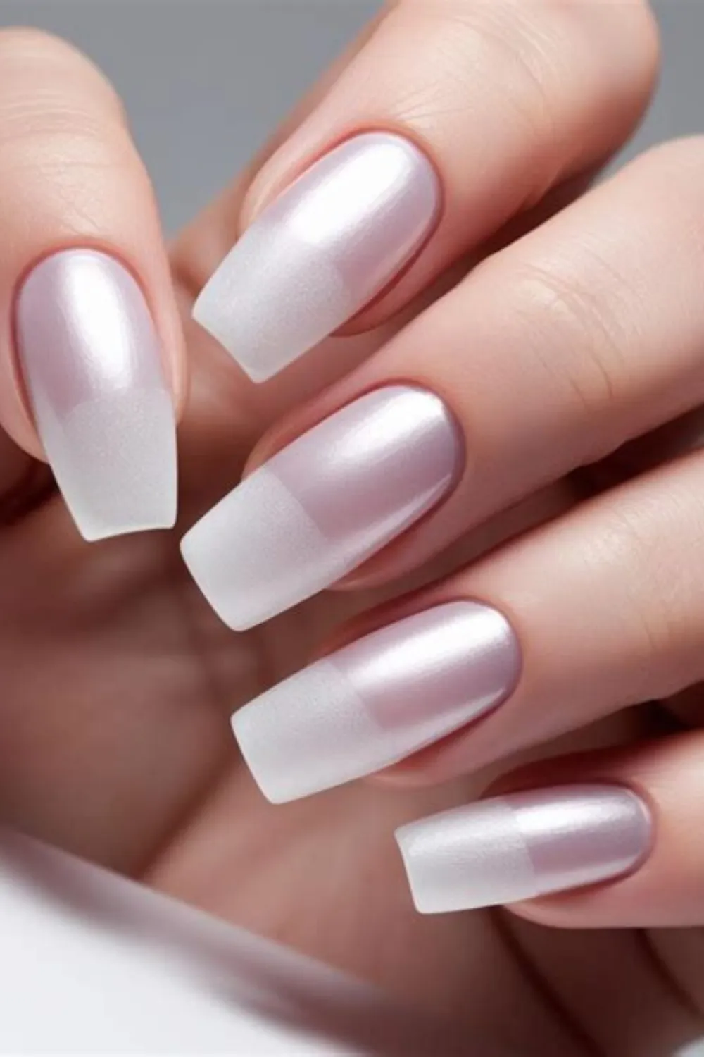 A close-up photograph showcasing a classic early 2000s frosted frosted French manicure on long, square-cut nails. The nail design features a subtle, pearlescent pinkish-white chrome base coat that transitions into crisp, frosted white square tips, giving off a retro, metallic ice-queen aesthetic popular in Y2K beauty trends.