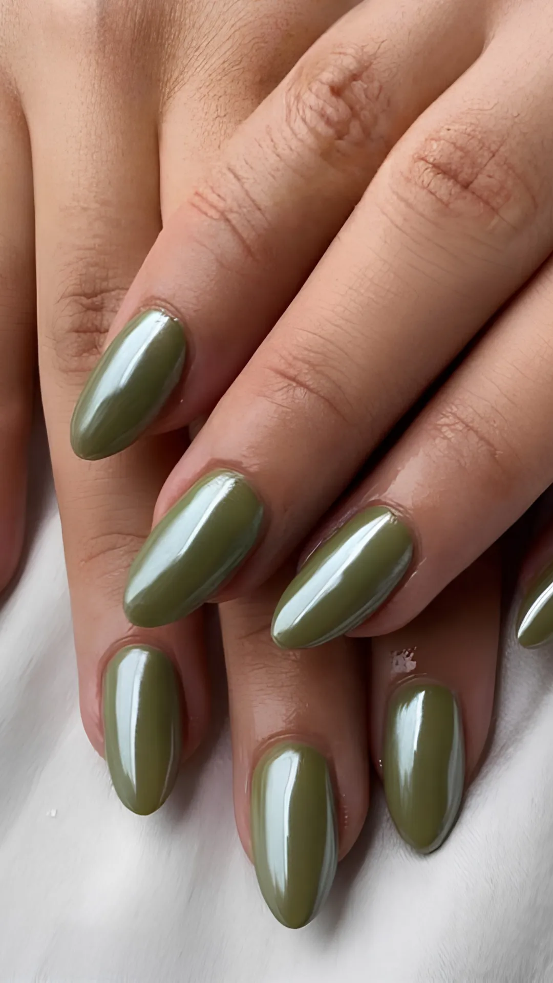A sophisticated chrome manicure featuring medium-length oval nails finished with a highly reflective, liquid metallic olive green glaze.
