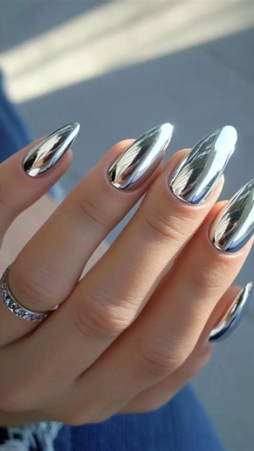 High-shine liquid mirror manicure showing long, flawless stiletto nails with a perfect reflective metallic silver chrome finish.