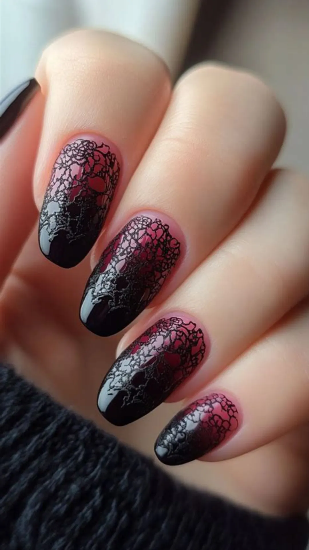 Dramatic gothic manicure displaying long oval nails with a vibrant red-to-black ombre base, intricately layered with fine black fishnet and rose lace nail stamp patterns.