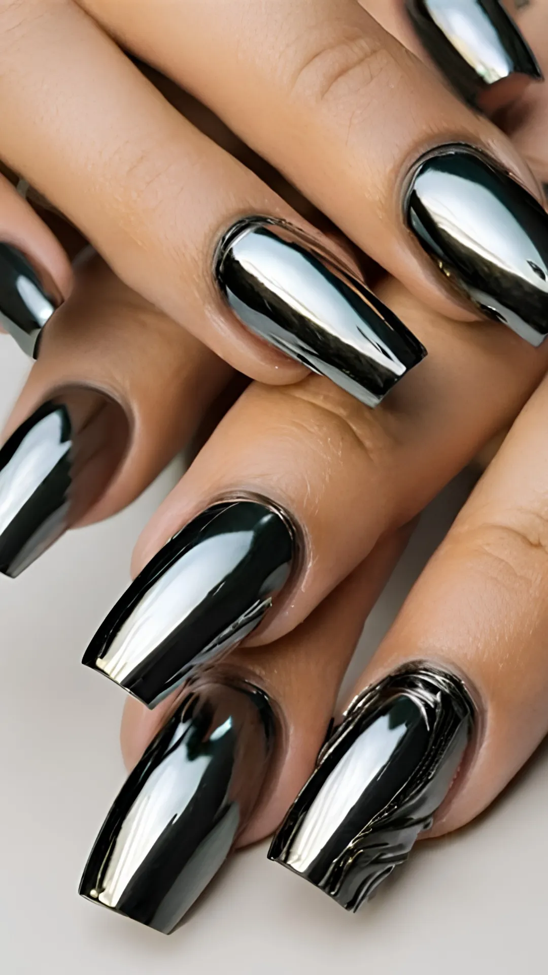 A close-up of a stunning, futuristic manicure showcasing long, square-shaped nails painted in a highly reflective, liquid mirror black chrome finish.
