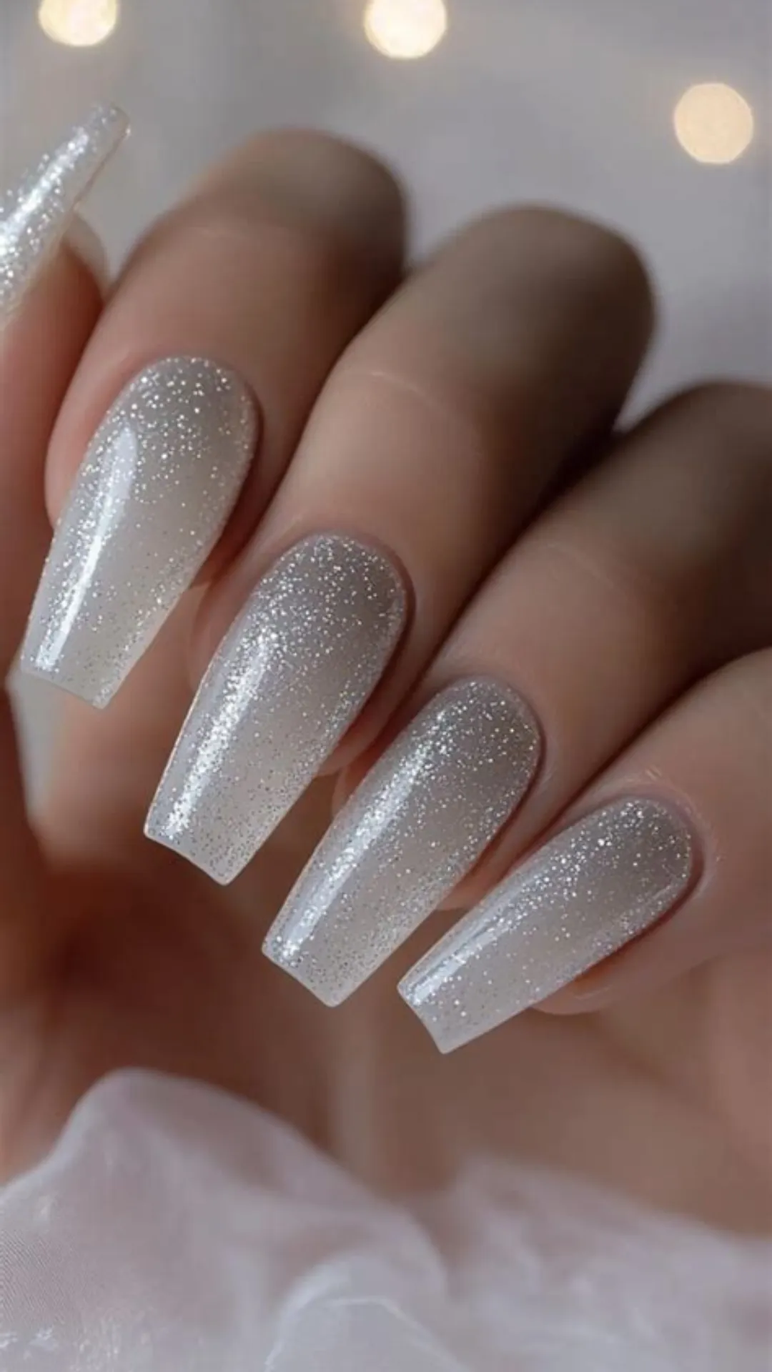 Glamorous long coffin nails featuring a milky translucent base coated in an all-over dusting of brilliant, fine silver glitter shimmer.