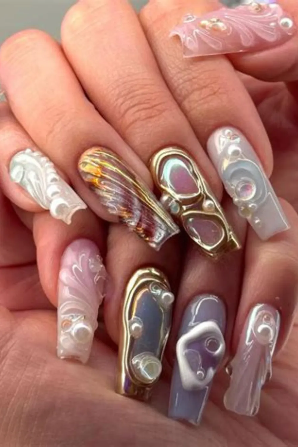 An extreme macro photograph showcasing a complex, 3D textured gel manicure on long coffin nails. The intricate art incorporates melted gold chrome accents, liquid-like clear gel droplets, iridescent opal foils, and clusters of faux pearls embedded over sheer milky pink and lavender bases, creating an ornate, futuristic jewelry-like effect on the fingertips.