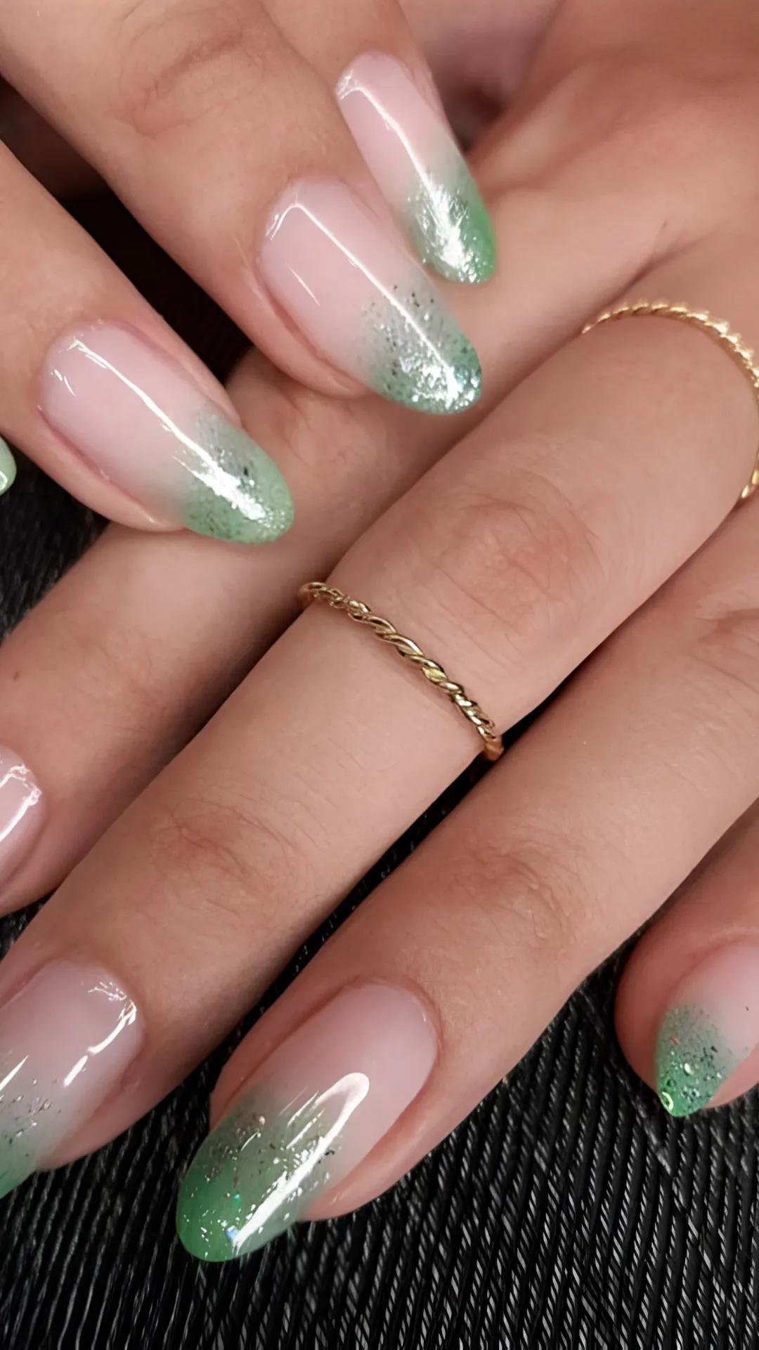 A soft and magical glitter ombre manicure on oval nails, transitioning seamlessly from a sheer nude base into shimmering, sparkling sage and olive green tips.