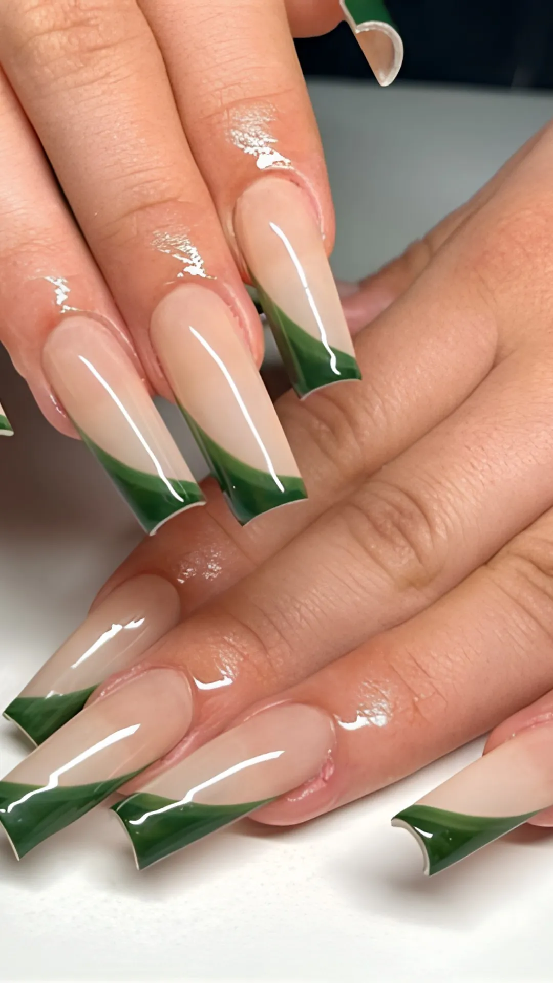 Dramatic long square acrylic nails showcasing a high-gloss nude base decorated with deep olive green side-swept, wavy French tips.