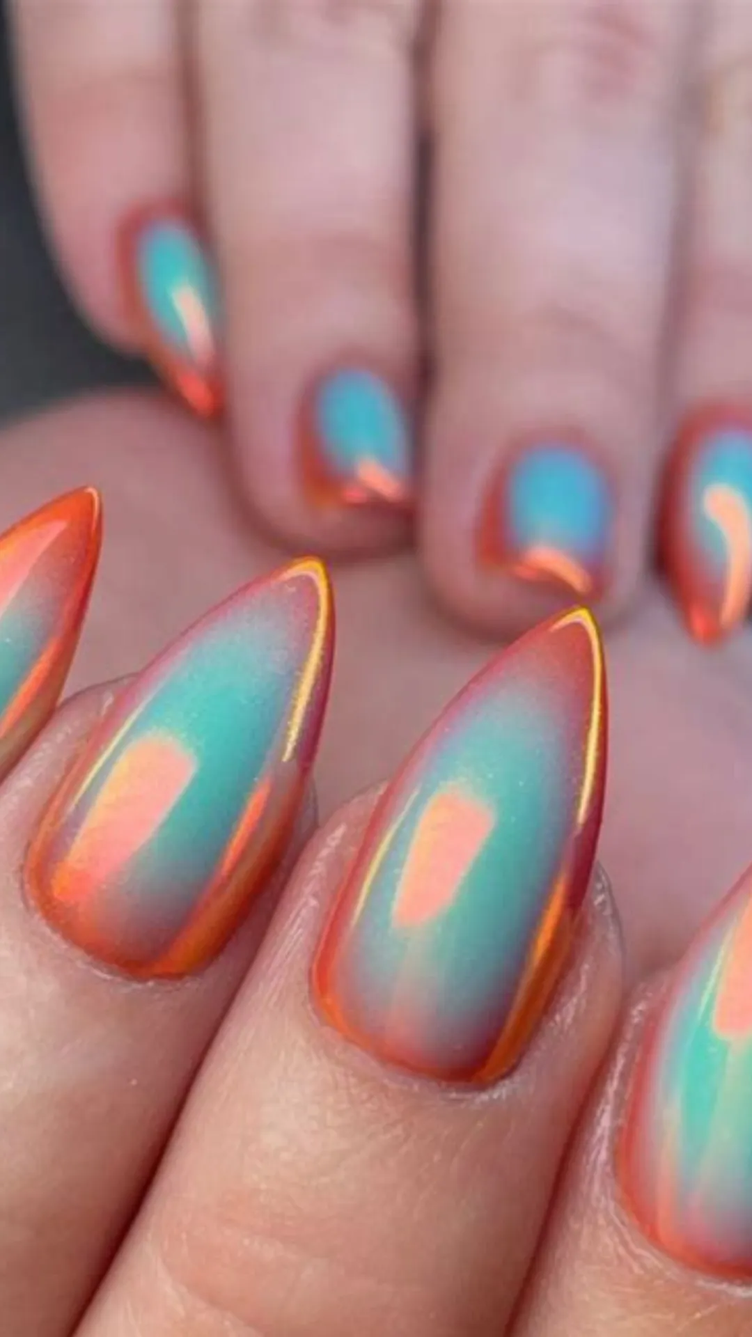 This close-up image features two hands with short, rounded nails, each showcasing a unique abstract geometric gel design against a light taupe or nude base. Each nail is a separate canvas, featuring an eclectic mix of thin lines, solid color blocks, and dots in light blue, teal, orange, pink, black, and white. The placement is random but balanced, creating a playful and artistic aesthetic. For instance, the index finger features a pink curve, while the middle finger displays black and white lines. The overall look is modern, minimal, and creative, offering a sophisticated way to wear multiple colors simultaneously.